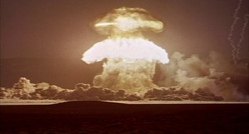 Movie still from “Naqoyqatsi” (2002), directed by Godfrey Reggio – A mushroom cloud is shown in the sky; Extreme Wide shot, Low angle