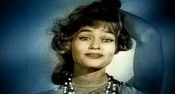 Movie still from “Naqoyqatsi” (2002), directed by Godfrey Reggio – A young woman with long hair and a necklace is posing for the camera; Close Up shot, Low angle