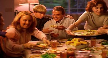 Movie still from “Naqoyqatsi” (2002), directed by Godfrey Reggio – A group of people sitting around a table eating food; Medium shot, High angle