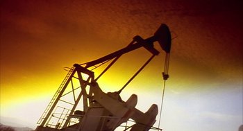 Movie still from “Naqoyqatsi” (2002), directed by Godfrey Reggio – An image of an oil rig in the middle of the night; Extreme Wide shot, Low angle