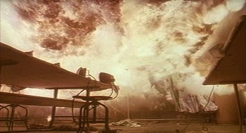 Movie still from “Naqoyqatsi” (2002), directed by Godfrey Reggio – An explosion is seen in the background of this picture; Extreme Wide shot, Low angle