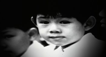 Movie still from “Naqoyqatsi” (2002), directed by Godfrey Reggio – A black and white photo of a young boy; Extreme Close Up shot, High angle