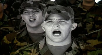 Movie still from “Naqoyqatsi” (2002), directed by Godfrey Reggio – Two men in military fatigues singing together; Close Up shot, Low angle