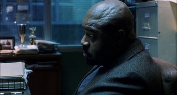 Movie still from “Narc” (2002), directed by Joe Carnahan – A bald man sitting in a chair in front of a window; Close Up shot, Over the shoulder angle