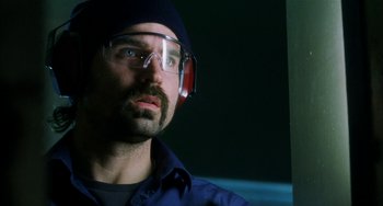 Movie still from “Narc” (2002), directed by Joe Carnahan – A man wearing safety glasses and a blue shirt; Close Up shot, Low angle