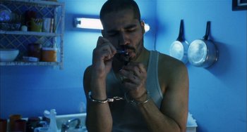 Movie still from “Narc” (2002), directed by Joe Carnahan – A man in handcuffs looking at a cell phone; Medium shot, Low angle