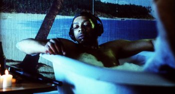 Movie still from “Narc” (2002), directed by Joe Carnahan – A man with headphones is sitting in a tub; Medium shot, Low angle