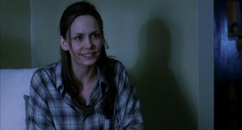 Movie still from “Narc” (2002), directed by Joe Carnahan – A woman in a plaid shirt smiling for the camera; Close Up shot, Over the shoulder angle