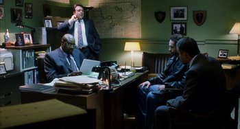 Movie still from “Narc” (2002), directed by Joe Carnahan – A group of men sitting at a table in front of a laptop; Medium shot, High angle