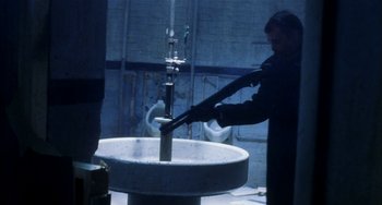 Movie still from “Narc” (2002), directed by Joe Carnahan – A man in a black jacket is working on a machine; Medium shot, Low angle