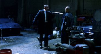 Movie still from “Narc” (2002), directed by Joe Carnahan – Two men in suits are talking to each other in an industrial setting; Wide shot, Over the shoulder angle