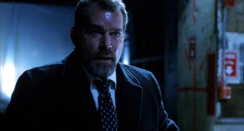 Movie still from “Narc” (2002), directed by Joe Carnahan – A man in a suit and tie in a dark room; Close Up shot, Low angle