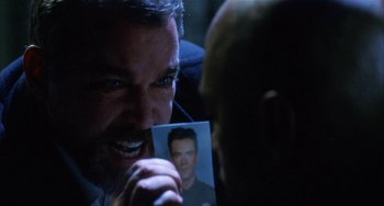 Movie still from “Narc” (2002), directed by Joe Carnahan – A man holding a picture of himself in a dark room; Close Up shot, Over the shoulder angle