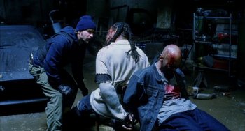 Movie still from “Narc” (2002), directed by Joe Carnahan – A group of people that are sitting on the ground; Medium shot, High angle