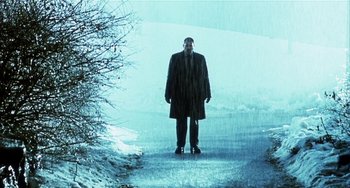 Movie still from “Narc” (2002), directed by Joe Carnahan – A man standing in the rain on the street; Wide shot, Low angle