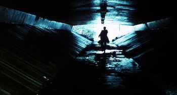 Movie still from “Narc” (2002), directed by Joe Carnahan – A man is walking through a tunnel in the dark; Extreme Wide shot, Low angle