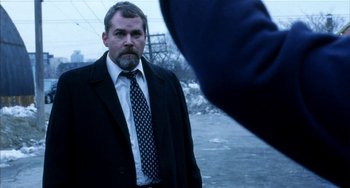 Movie still from “Narc” (2002), directed by Joe Carnahan – A man wearing a suit and tie standing in front of another man; Medium shot, Over the shoulder angle
