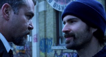 Movie still from “Narc” (2002), directed by Joe Carnahan – Two men standing next to each other in front of a building; Close Up shot, Over the shoulder angle