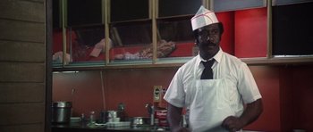 Movie still from “Nashville” (1975), directed by Robert Altman – A man wearing a white hat standing in front of a counter; Medium shot, Low angle