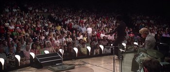 Movie still from “Nashville” (1975), directed by Robert Altman – A crowd of people sitting in front of a microphone; Wide shot, High angle