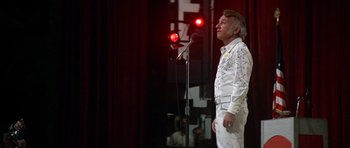 Movie still from “Nashville” (1975), directed by Robert Altman – A man standing in front of a microphone on a stage; Medium shot, Low angle