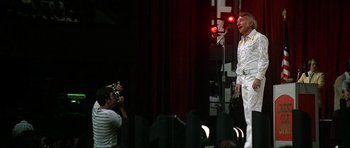 Movie still from “Nashville” (1975), directed by Robert Altman – A man standing on a stage while a photographer takes a picture of him; Wide shot, Low angle