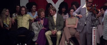Movie still from “Nashville” (1975), directed by Robert Altman – A group of people sitting around each other on a stage; Medium shot, High angle