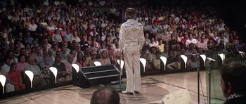 Movie still from “Nashville” (1975), directed by Robert Altman – A man in a white suit stands in front of an audience; Wide shot, Over the shoulder angle