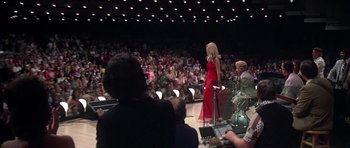 Movie still from “Nashville” (1975), directed by Robert Altman – A woman in a red dress speaking to an audience in front of an orchestra; Wide shot, Low angle