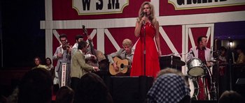 Movie still from “Nashville” (1975), directed by Robert Altman – A woman in a red dress singing into a microphone while holding a guitar; Medium shot, Over the shoulder angle
