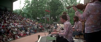Movie still from “Nashville” (1975), directed by Robert Altman – A group of people sitting on a stage with musical instruments; Extreme Wide shot, High angle
