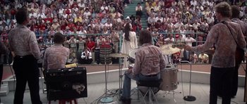 Movie still from “Nashville” (1975), directed by Robert Altman – A man sitting on top of a drum set in front of an audience; Wide shot, High angle