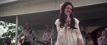 Movie still from “Nashville” (1975), directed by Robert Altman – A woman is singing into a microphone while a man plays guitar; Medium shot, Low angle