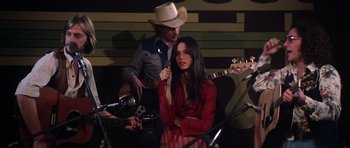 Movie still from “Nashville” (1975), directed by Robert Altman – A woman in a cowboy hat is holding a microphone; Medium shot, High angle