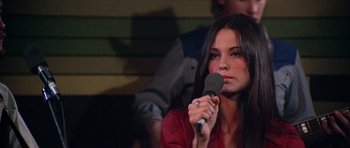 Movie still from “Nashville” (1975), directed by Robert Altman – A woman is holding a microphone up to her mouth; Close Up shot, Over the shoulder angle
