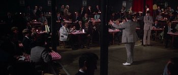 Movie still from “Nashville” (1975), directed by Robert Altman – A group of people sitting at tables in front of a crowd; Wide shot, Over the shoulder angle