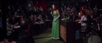 Movie still from “Nashville” (1975), directed by Robert Altman – A woman in a green dress is on a stage; Wide shot, Over the shoulder angle