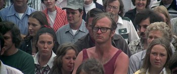Movie still from “Nashville” (1975), directed by Robert Altman – A crowd of men and women standing around a building; Close Up shot, Over the shoulder angle
