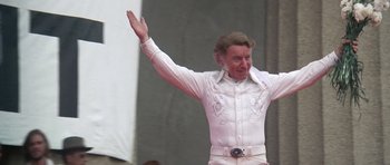 Movie still from “Nashville” (1975), directed by Robert Altman – A man in a white shirt is waving his hand; Medium shot, Low angle