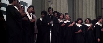 Movie still from “Nashville” (1975), directed by Robert Altman – A group of people standing next to a microphone; Medium shot, High angle