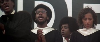 Movie still from “Nashville” (1975), directed by Robert Altman – A man in a graduation cap and gown is singing; Close Up shot, Low angle