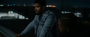 Movie still from “National Champions” (2021), directed by Ric Roman Waugh – A man in a denim jacket is standing next to a woman; Close Up shot, Over the shoulder angle