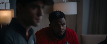 Movie still from “National Champions” (2021), directed by Ric Roman Waugh – A man in a red shirt is looking at another man in a red shirt; Close Up shot, Over the shoulder angle