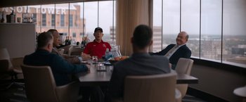Movie still from “National Champions” (2021), directed by Ric Roman Waugh – A group of people sitting at a table with food; Medium shot, Over the shoulder angle