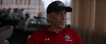 Movie still from “National Champions” (2021), directed by Ric Roman Waugh – An older man wearing a red shirt and a black hat; Close Up shot, Over the shoulder angle