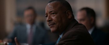 Movie still from “National Champions” (2021), directed by Ric Roman Waugh – A man in a brown suit and a blue tie; Close Up shot, Low angle