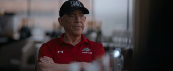 Movie still from “National Champions” (2021), directed by Ric Roman Waugh – An older man wearing a red shirt and a black hat; Close Up shot, Over the shoulder angle
