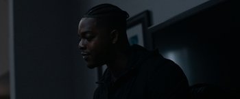 Movie still from “National Champions” (2021), directed by Ric Roman Waugh – A man with a black shirt is looking to his left; Close Up shot, Over the shoulder angle