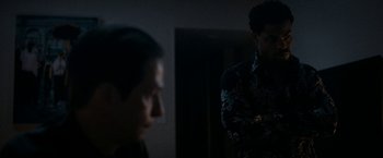 Movie still from “National Champions” (2021), directed by Ric Roman Waugh – Two men are standing in a dark room; Medium shot, Over the shoulder angle