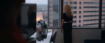 Movie still from “National Champions” (2021), directed by Ric Roman Waugh – A woman standing in front of a window looking out at a city; Wide shot, Over the shoulder angle